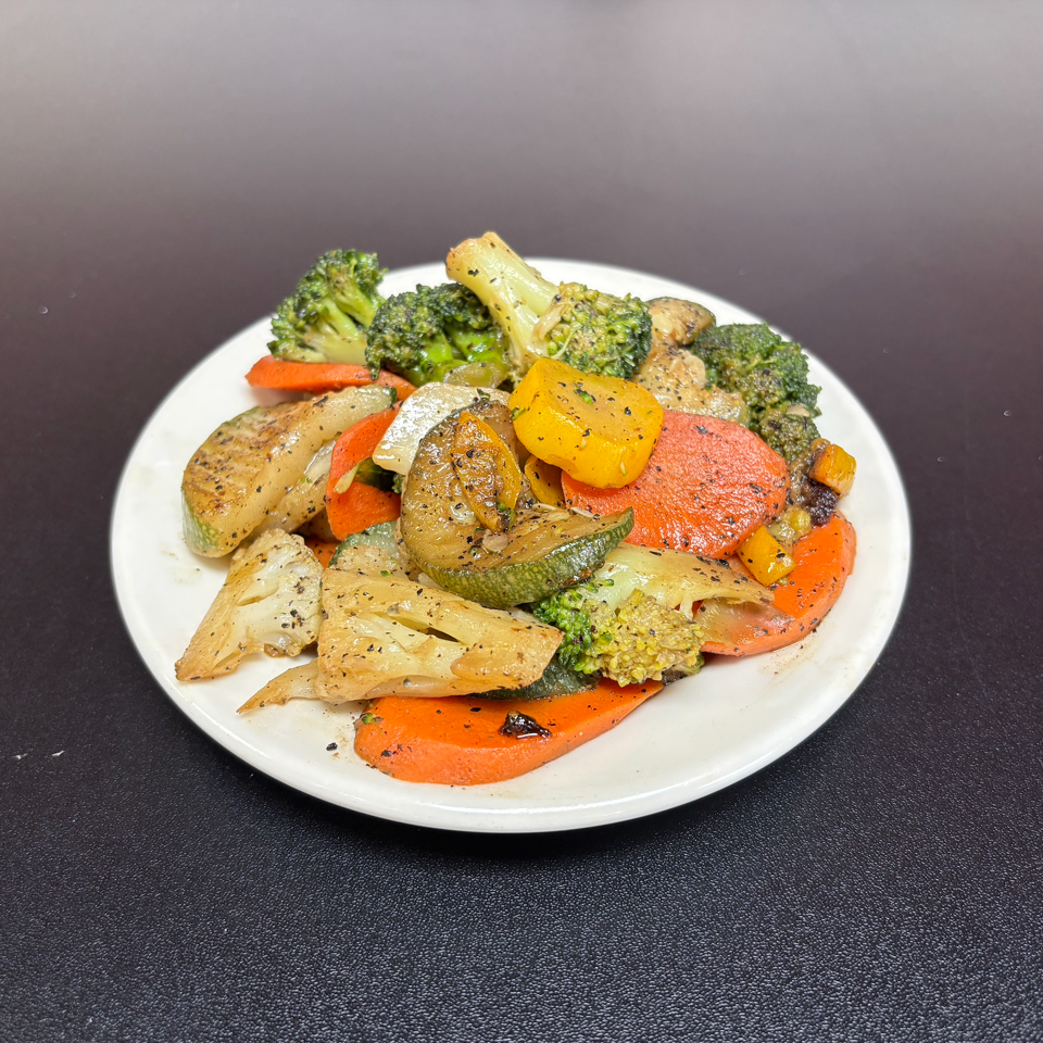 Plate of seasoned roasted vegetables, including broccoli, carrots, zucchini, squash, onions, and peppers.